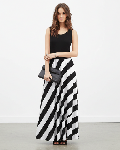 Woman wearing a black sleeveless top and black and white striped skirt with a gray clutch.