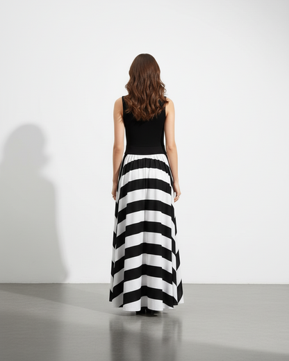 Woman wearing a striped long dress with maxi skirt on a plain background