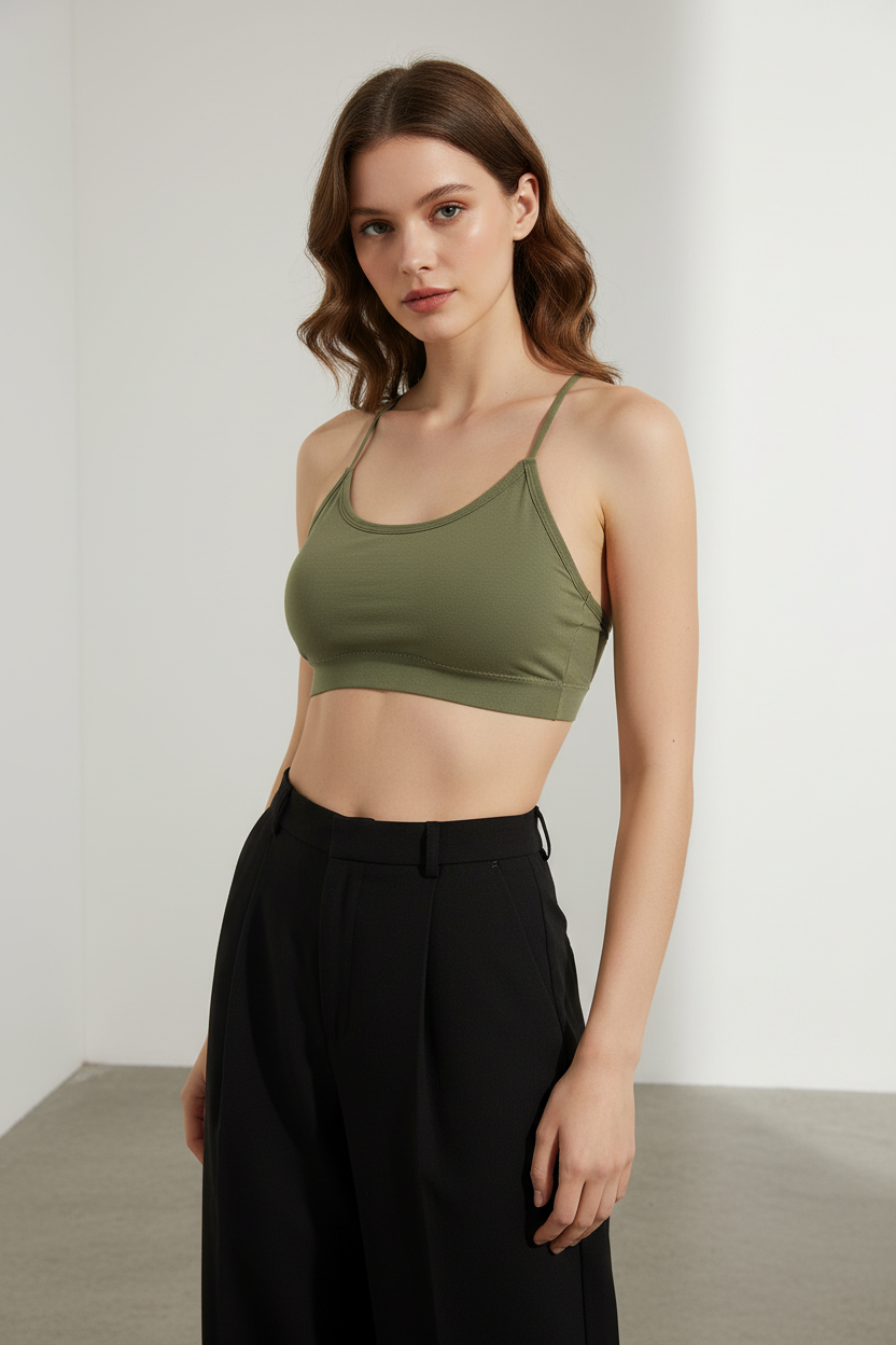 Woman wearing a green sports bra and black pants against a white background