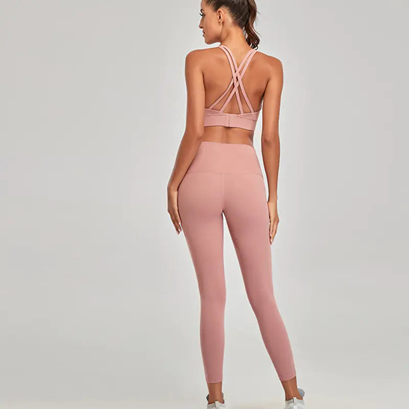 Woman wearing a pink sports bra and leggings set on a plain background