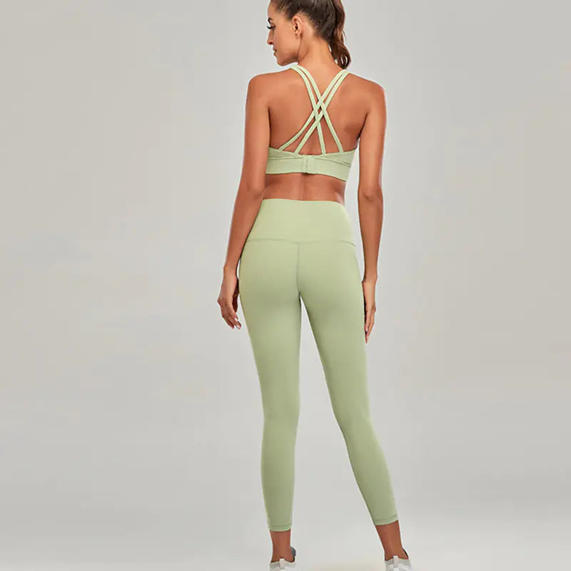 Woman wearing a green sports bra and leggings set on a plain background
