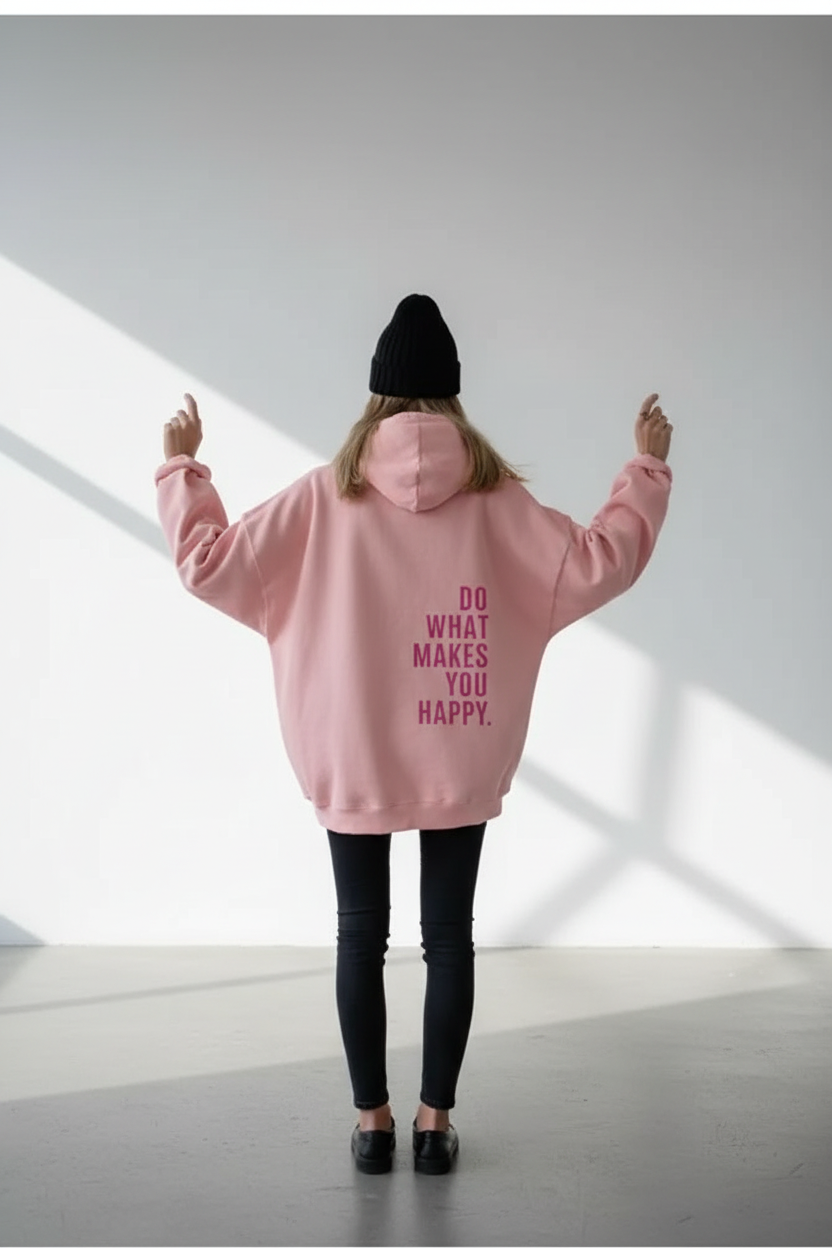 Person wearing a pink hoodie with text, standing in a minimalistic room.