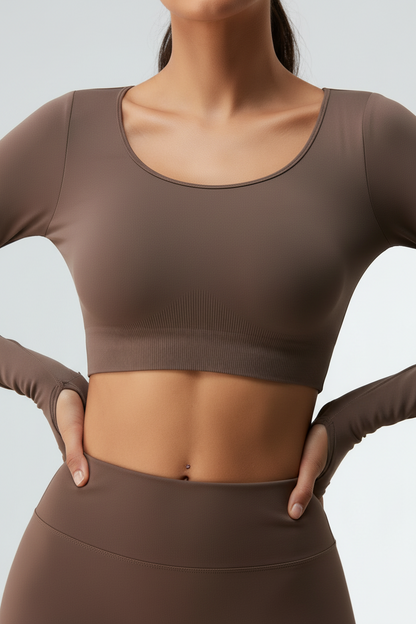 Person wearing a brown long-sleeve crop top and leggings on a light gray background