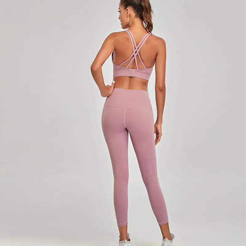 Woman wearing a pink sports bra and leggings set on a gray background