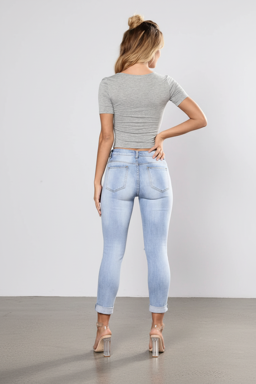 Woman wearing a gray crop top and light blue jeans against a white background