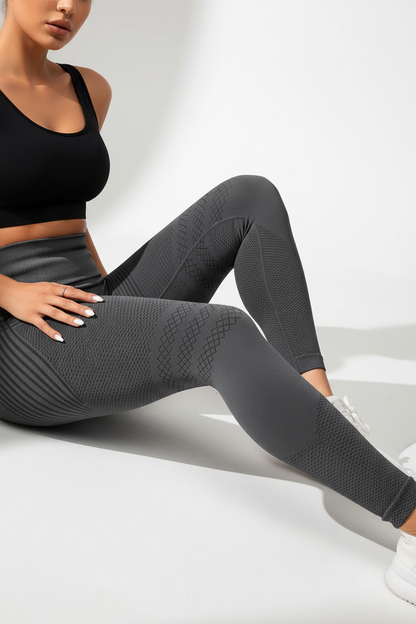 Person wearing black sports bra and gray leggings sitting on a white surface.