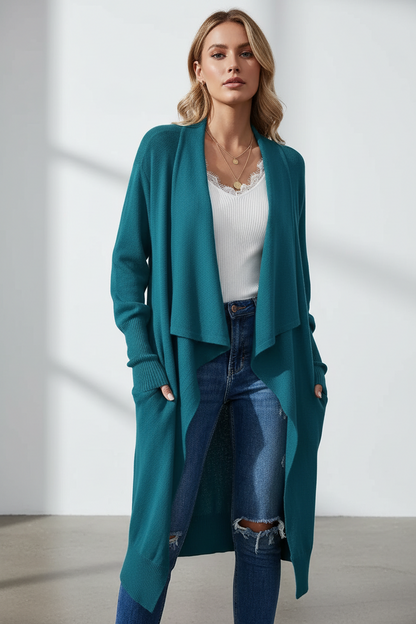 Woman wearing a teal cardigan, white top, and blue jeans against a white background