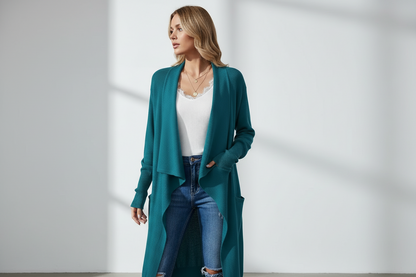 Woman wearing a teal cardigan, white top, and blue jeans against a white background