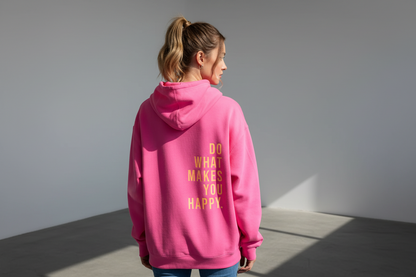 Person wearing a pink hoodie with text on the back, standing against a plain wall.