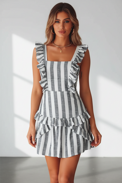 Woman wearing a black and white striped dress with ruffled details on a light background