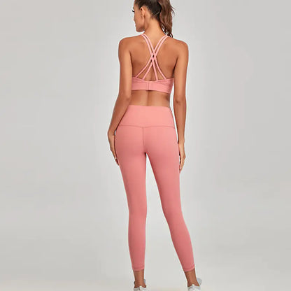 Woman wearing a pink sports bra and leggings set on a gray background