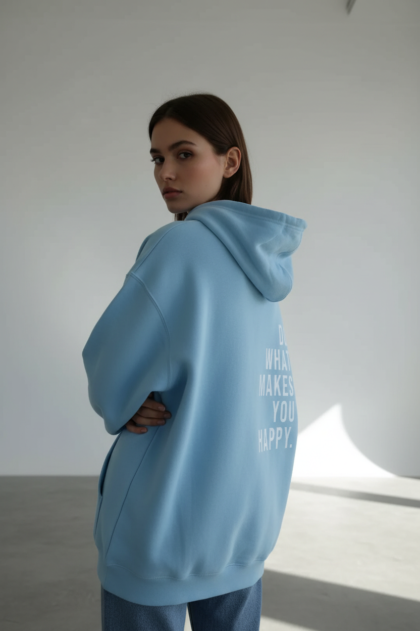 Person wearing a light blue hoodie with text, standing in a minimalistic room.