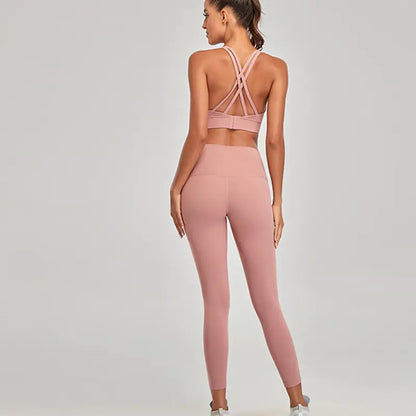 Woman wearing a pink sports bra and leggings set on a plain background