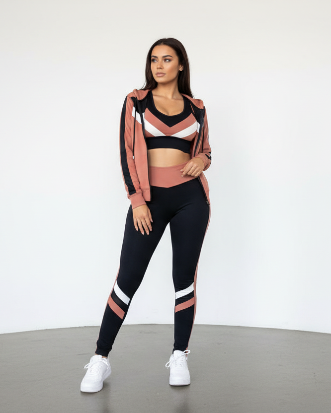 Woman wearing a sports outfit with a pink jacket, black leggings, and white sneakers on a plain background