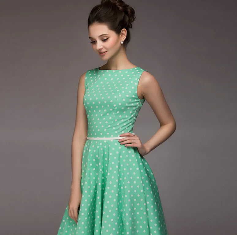 Woman wearing a green dress with white polka dots against a gray background