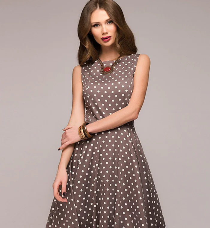 Woman wearing a brown dress with white polka dots against a gray background