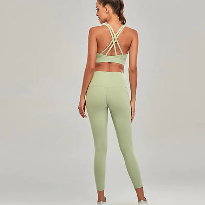 Woman wearing a green sports bra and leggings set on a plain background