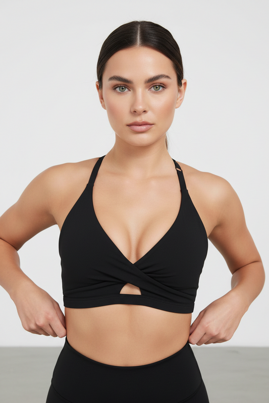 Woman wearing a black sports bra with a cutout design on a white background