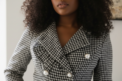 Woman wearing a black and white houndstooth patterned coat with pearl buttons.