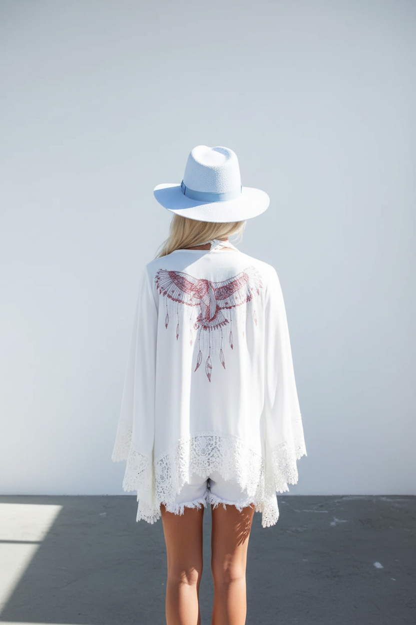 Person wearing a white lace cover-up and a white hat against a light gray background